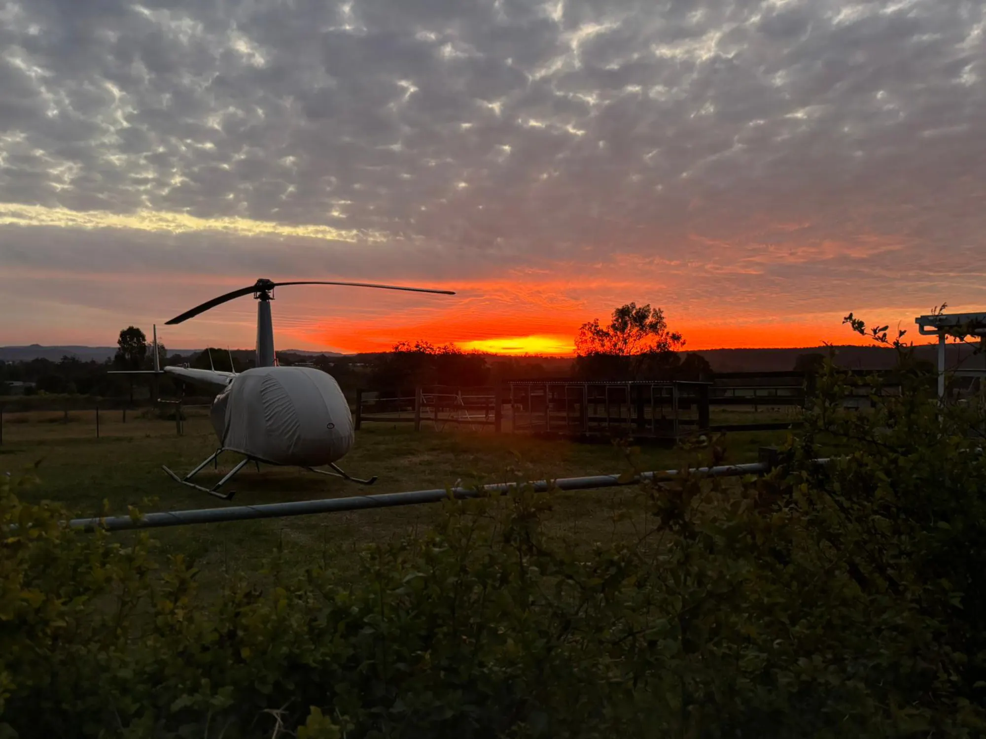 Helicopter parked at sunset under an orange sky