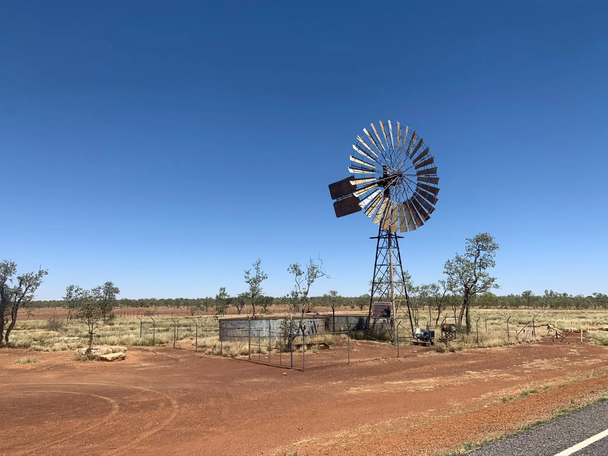 Outback windmill on red dirt under deep blue sky