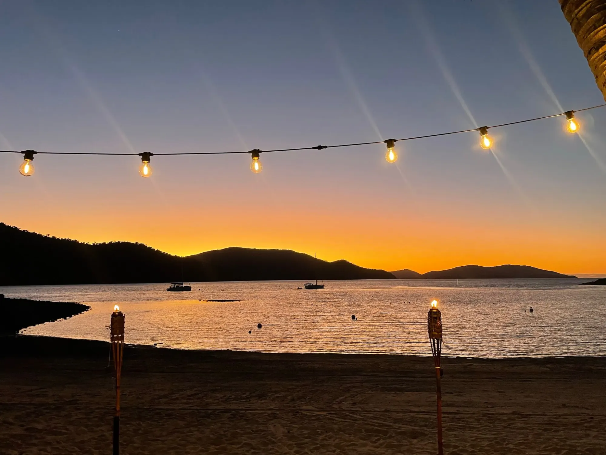 Tropical beach at sunset with string lights overhead