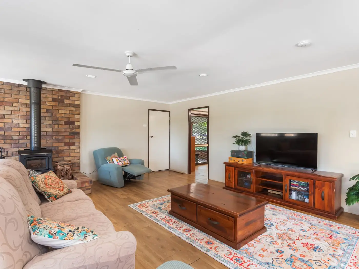 Open-plan living room with a brick fireplace and timber floors